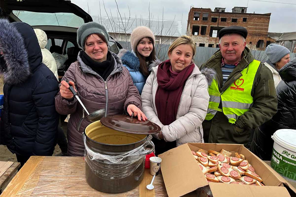 Ukrainian volunteers offer soup and sandwiches by the train tracks. © A. Borden